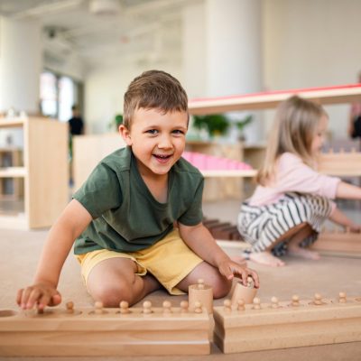 Group of small nursery school children playing indoors in classroom, montessori learning